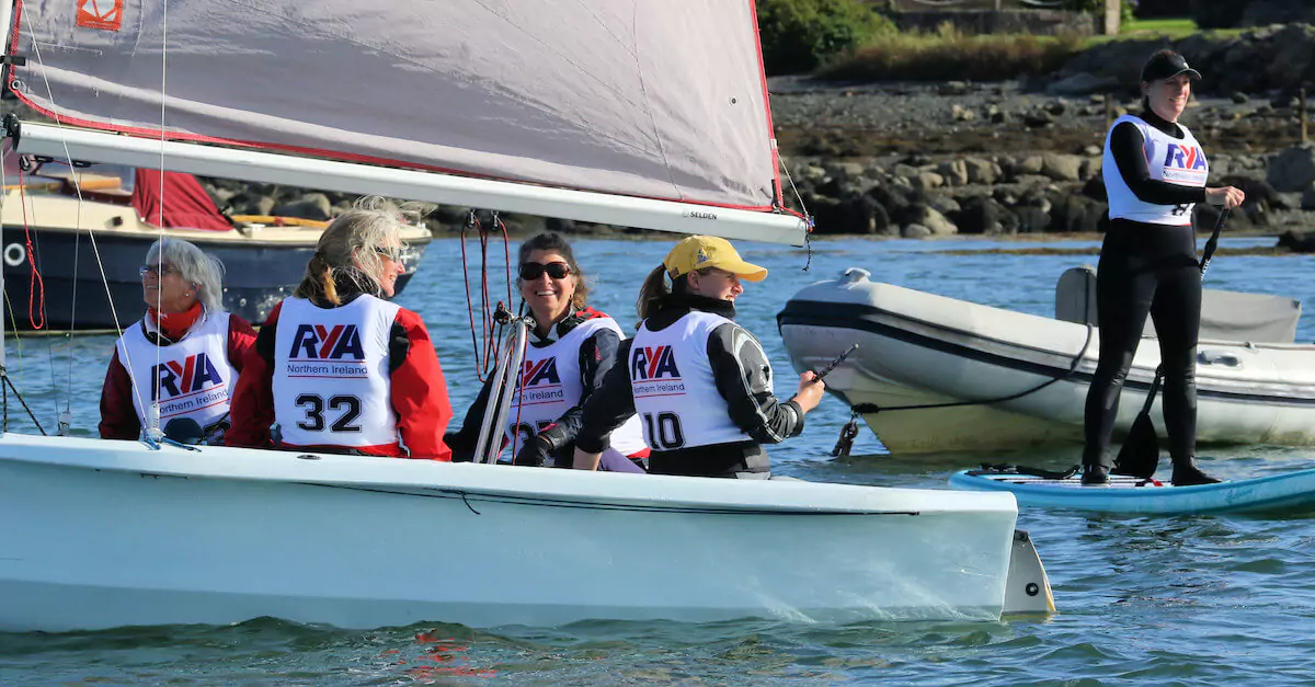 Women sailing on small boat wearing RYA bibs
